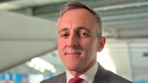 Labour's Sunderland Central MP Lewis Atkinson. He has grey hair and is wearing a red tie.